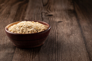 Oat flakes in wooden bowl.