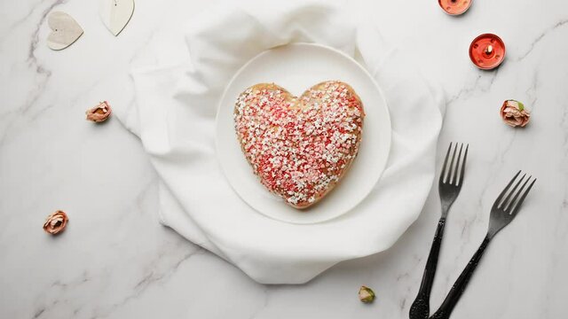Valentines day food. Woman puts heart shaped cake on table for Valentine's Day. Table top view.