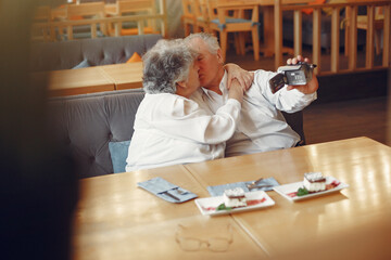 Elegant old couple in a cafe using a camera