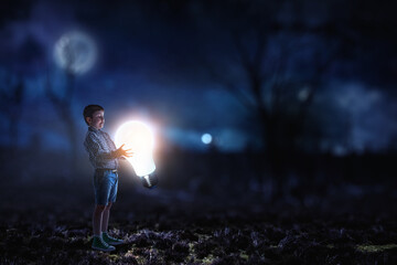 Boy standing next to a light bulb