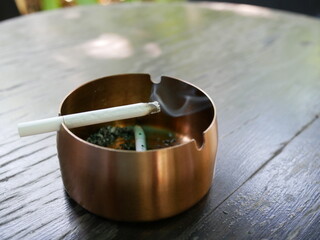 burning cigarette on aluminum ashtray.	