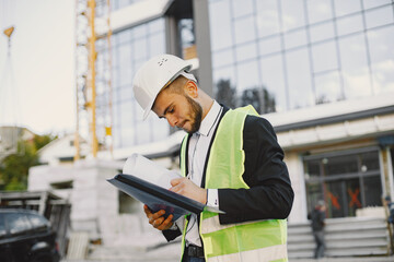 European engineer in helmet looking at paper plan