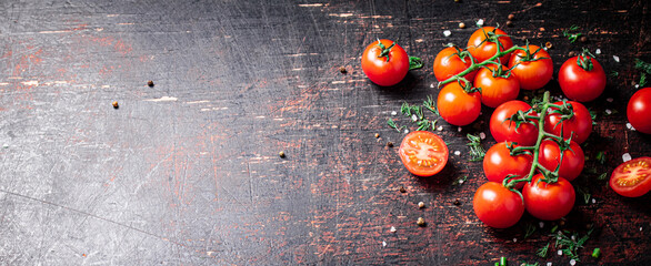 Fototapeta Tomatoes on a branch with pieces of greens and spices. Against a dark background. High quality photo obraz