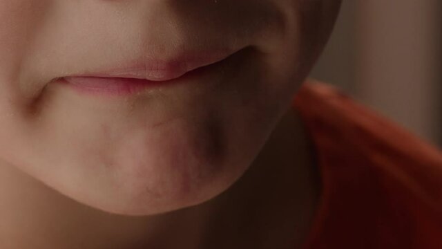 Close up portrait of a child's lips and mouth changing from pouting to smiling.