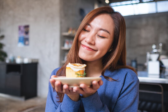 Portrait image of a young asian woman holding and eating a piece of lemon pound cake