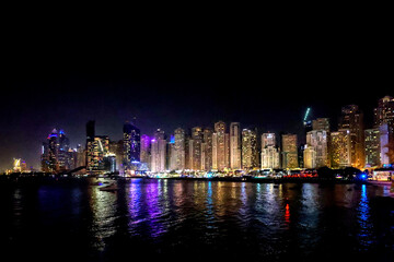 Panoramic view at night of Business Bay district with reflection in sea, UAE. Aerial sky at highest buildings in central Dubai, United Arab Emirates. High quality photo