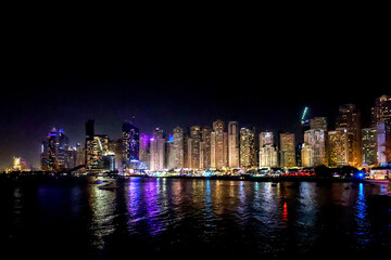 Obraz premium Panoramic view at night of Business Bay district with reflection in sea, UAE. Aerial sky at highest buildings in central Dubai, United Arab Emirates. High quality photo