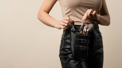 Thigh bag with different brushes on faceless professional makeup artist. Unrecognizable make-up...