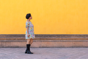A mid adult afro mexican woman walking in front of a yellow wall - Powered by Adobe