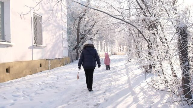 Grandmother with granddaughter walking in snow on nice winter day.