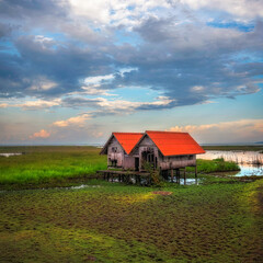 Old twin houses in the grass fields with beautiful clouds and sky during sunset time. It has ever been the shelter for farmer.