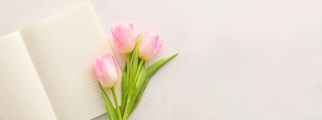 Blank notebook and tulips on light background with space for text
