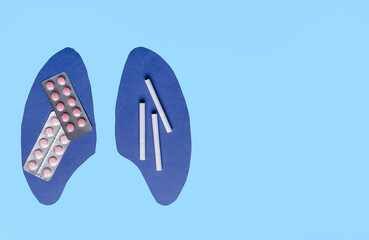 Paper human lungs with pills and cigarettes on color background