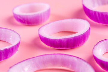 Sliced red onion rings isolated on pink background.