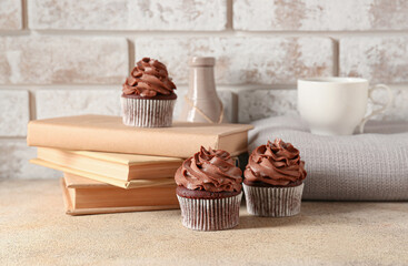 Tasty chocolate cupcakes with books on table