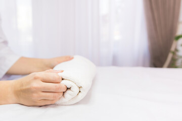 Cropped photo of hands holding rolled white towel on the table in the clinic spa salon, skin care concept.
