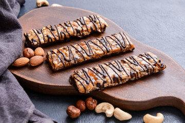 Board with tasty chocolate nut bars on dark background