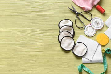 Handmade cotton pads with materials on color wooden background