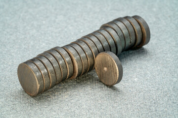 stack of small round ceramic ferrite magnets on textured gray  paper