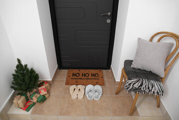 Interior of modern hallway with mat, slippers, chair and Christmas decor