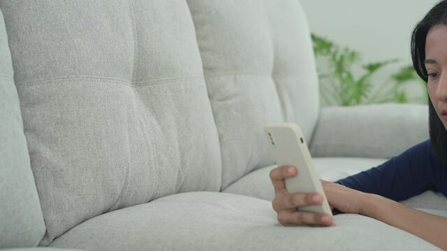 A beautiful Asian woman looks smartphone messages and has a depressed and disappointed expression on face. sad and alone people. Cyber bullying concept.