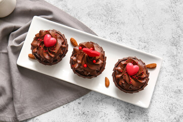 Plate with tasty chocolate cupcakes for Valentine's day on light background
