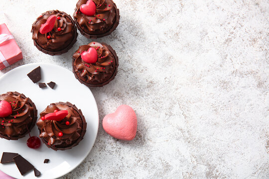 Plate with tasty chocolate cupcakes for Valentine's day on light background