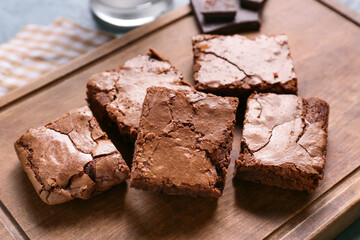 Wooden board with pieces of tasty chocolate brownie on table