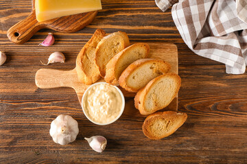 Board of tasty croutons with sauce on wooden background