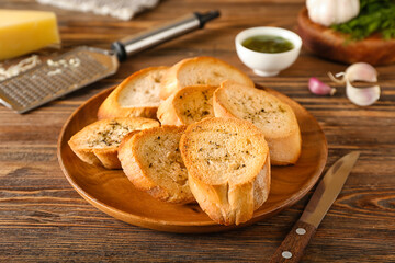 Plate of tasty croutons on wooden background