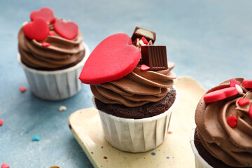 Plate with tasty chocolate cupcakes for Valentine's Day on blue background