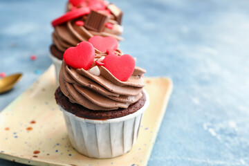 Plate with tasty chocolate cupcakes for Valentine's Day on blue background