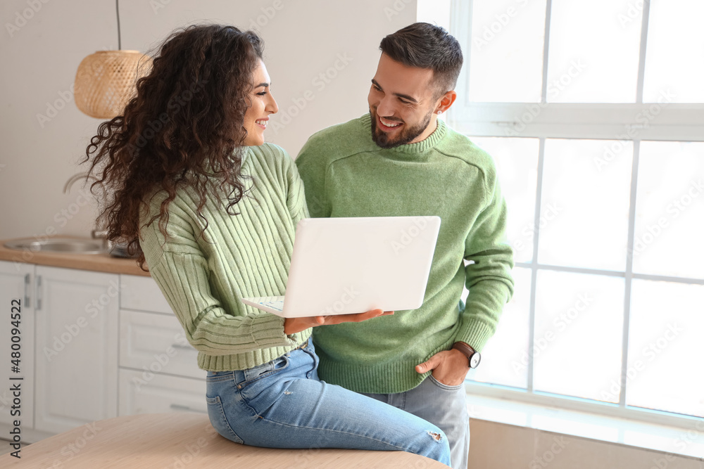 Sticker Young couple using laptop in kitchen