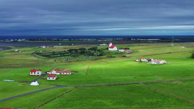 Typical Houses With Church And Cemetery Surrounded With Green Grassland In Gardakirkjugardur, Gardabaer, Iceland. - aerial