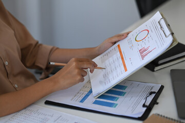 Businesswoman checking financial graph at office desk.