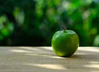 Green apple on wood and blurred natural background