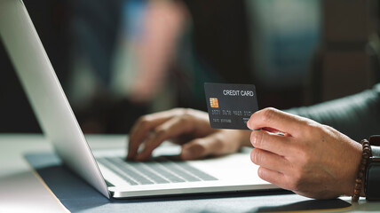 Young man with credit card shopping over portable tablet  while sitting at cafe. Online payment, shopping online. Dark tone color.
