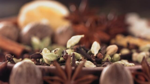 Cardamom and Clove falling among Spices on wood. Slow motion