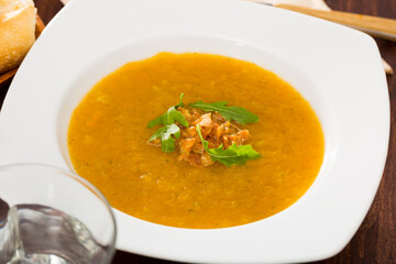 Dietary cream soup of vegetables garnished with caramelized onion and fresh arugula ..