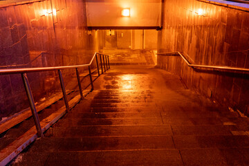 descending into an underground pedestrian crossing at night, poorly lit underground passages in a megalopolis, crossing a road through an underground passage in the evening, returning home