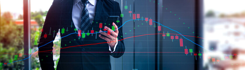 Double exposure of businessman's hands holding a smartphone and statistic graph of stock market on laptop screen