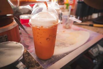 Making of Thai orange traditional milk tea with milk foam . street food ready for drink