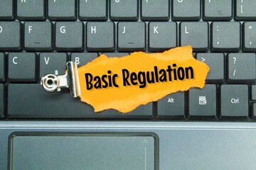 laptop keyboards and torn colored paper with the words basic regulation