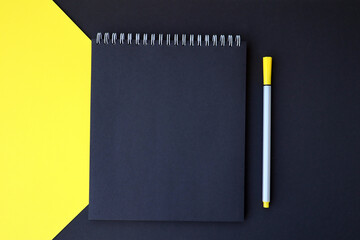 Mockup planner flat lay, top horizontal view yellow and black background. Black notepad with pen.