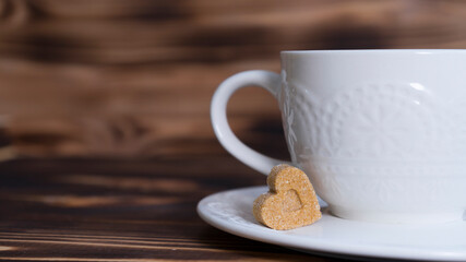 White beautiful cup with a piece of sugar in the shape of a heart