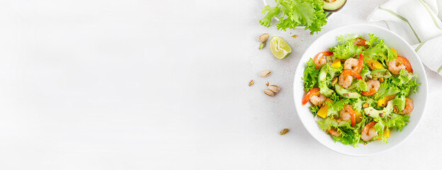 Grilled shrimp salad with avocado, mango, lettuce and pistachios, dressed with lime. Healthy food. Ketogenic diet. Top view. Banner.