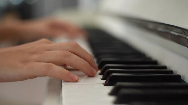 Extreme close-up hands of unrecognizable female pianist playing on classical piano calm gentle music during concert in light room. Closeup of lady student training to play piano in classrom.
