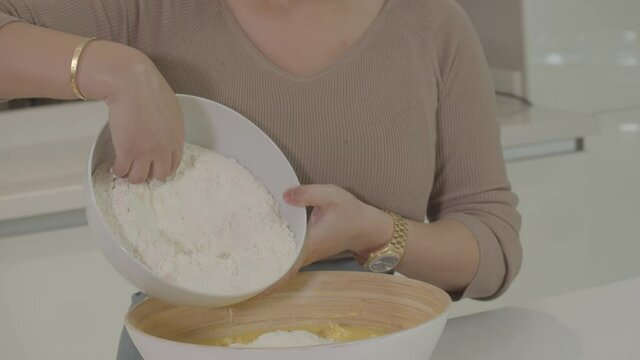 farine is added to the cake batter. video preparation for making cakes and bread. footage of activities in the kitchen