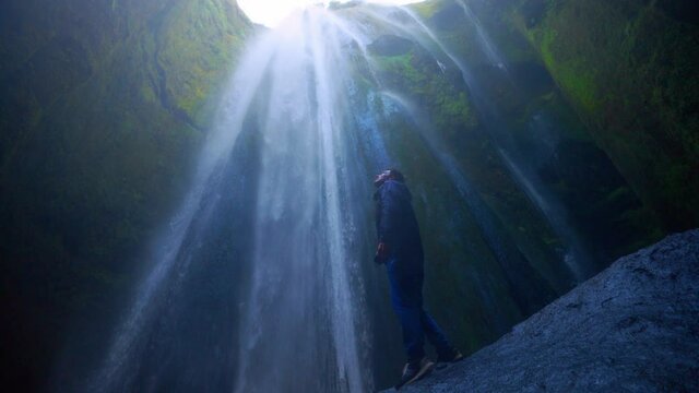 Man Standing And Rising His Arms On Beautiful Gljufrabui Waterfall In Iceland. Low Angle