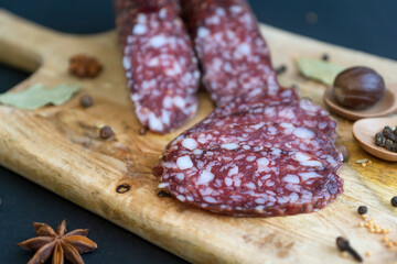 Smoked sausage and various spices on a wooden cutting board.